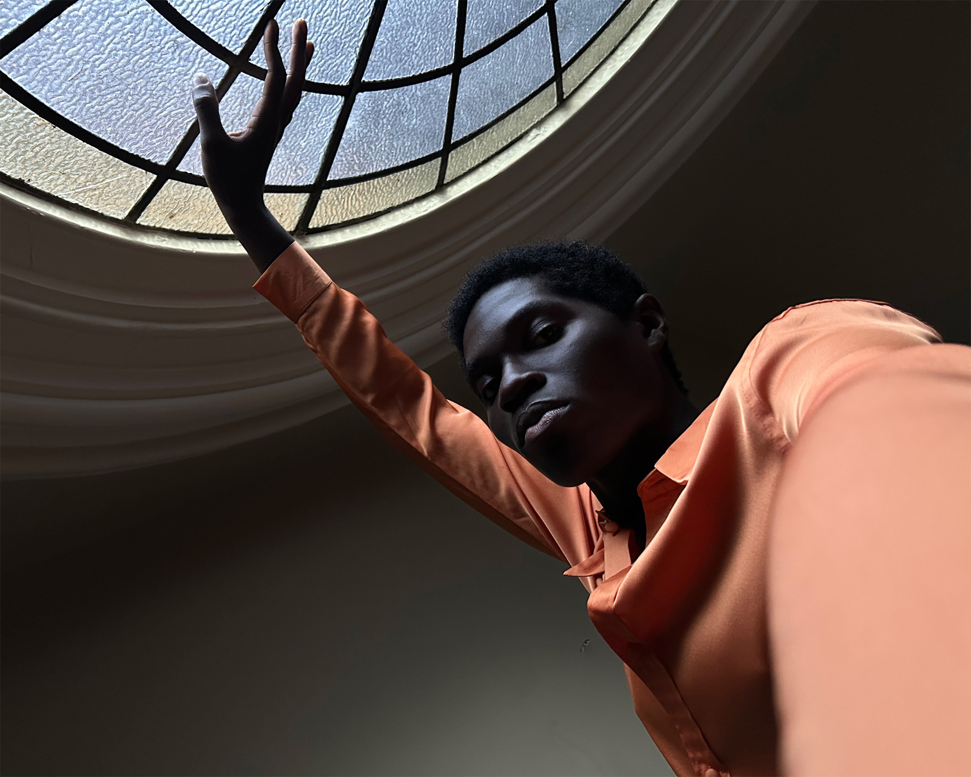 Phtonic Engine iPhone 14 Plus Homme levant la main sous un dôme de verre l'illuminant dans un bâtiment